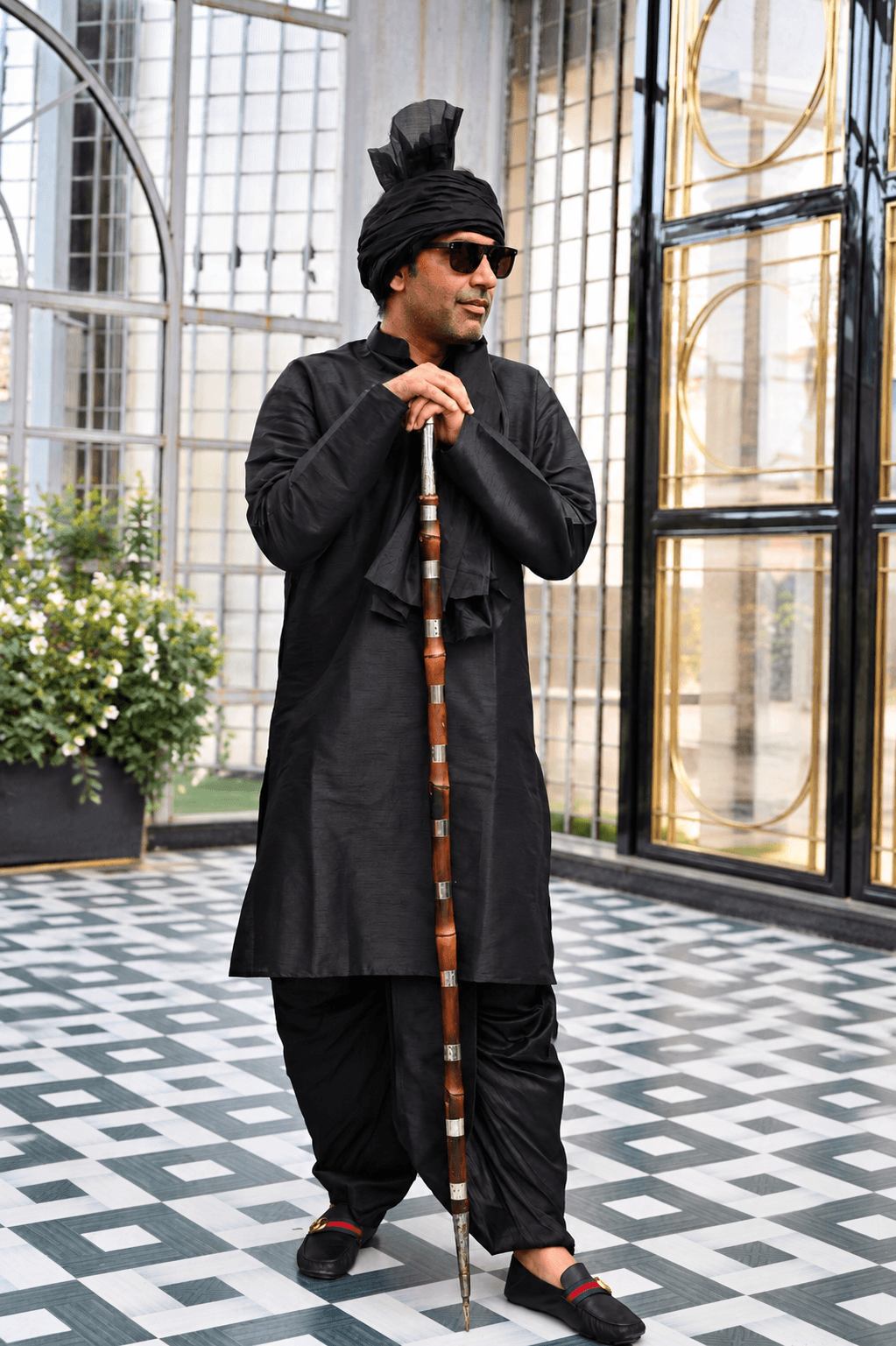 Gaurhav Nagar in a black traditional outfit holding a staff